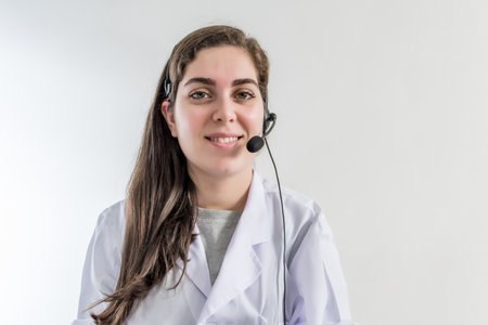 A shallow focus of a smiling healthcare consult with headphones against a gray wallの写真素材