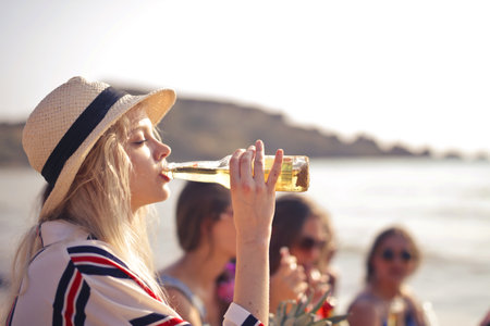 A young European female drinking beer from a bottleの写真素材