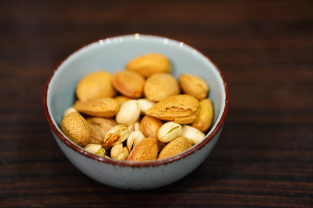 A closeup of a bowl of pistachios and almonds in shells on the tableの写真素材