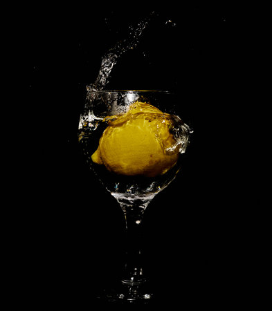 A vertical shot of a glass of water with lemon and splashes on an isolated backgroundの写真素材