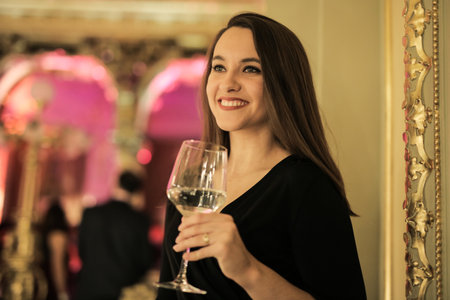 A portrait of a smiling female with a glass of wine on a luxury eventの写真素材