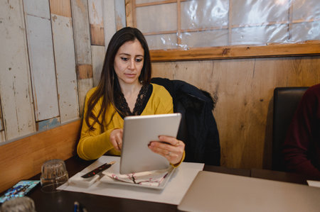 A beautiful Hispanic woman checking something on her tablet