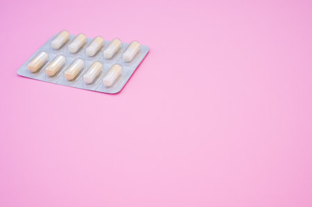 An isolated shot of the medicine capsules in a pad on a pink backgroundの写真素材