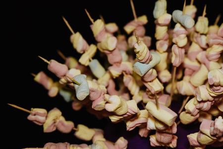 A closeup shot of sticks with colorful marshmallows on them on a black backgroundの写真素材