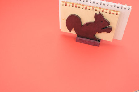 An isolated shot of the notebooks in the wooden squirrel paper holder on a pink background- free...
