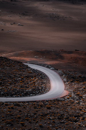 A scenic view of an empty curved road on the side of a hillの写真素材