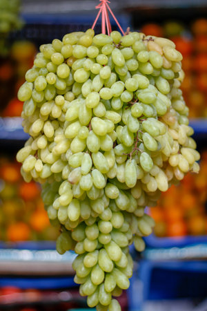 A vertical shot of green ripe grapes on a blurry background in the marketの写真素材