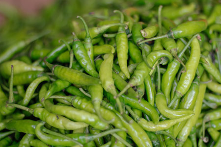 A big bucket filled with green spicy peppers in the market
