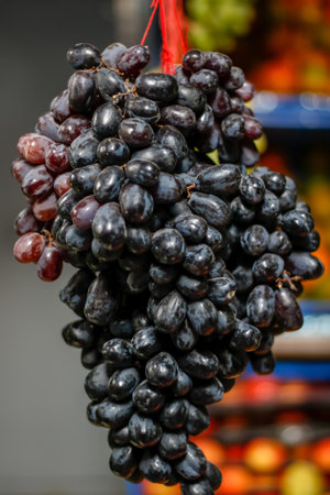 A vertical shot of black ripe grapes on a blurry background in the marketの写真素材
