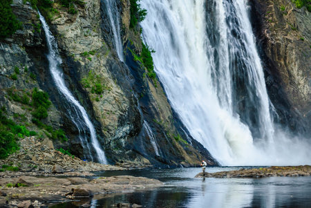 Man fishing at the base of Montmorency Falls, Quebec, Canadaの写真素材