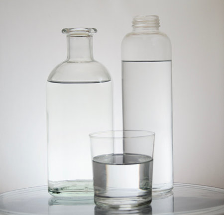 A glass and two bottles of water on a gray backgroundの写真素材