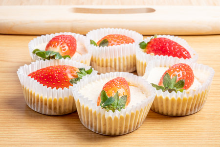 A closeup of the mini strawberry cheesecakes on the wooden tableの写真素材