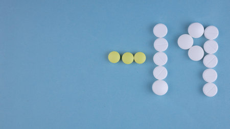 A top view of Covid-19 written with pills on a blue surface