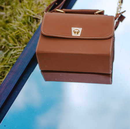 A vertical shot of a brown shoulder bag on a mirrorの写真素材