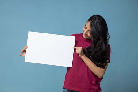 A Mexican Latin woman holding an empty blank board with space for textの写真素材