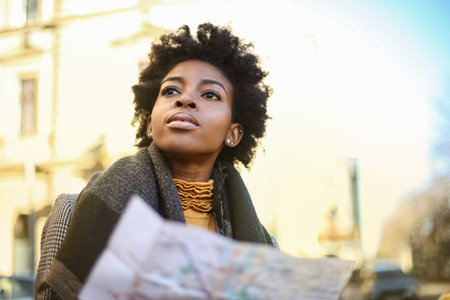 A shallow focus of a young African woman with short curly hair coordinating with a map outdoorsの写真素材