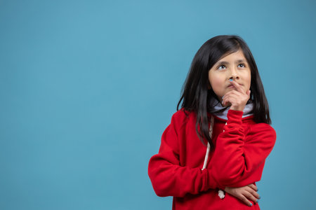 A Hispanic female child thinking isolated on a blue backgroundの写真素材