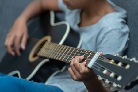 A Mexican boy playing the guitar at home - homeschooling concepの写真素材
