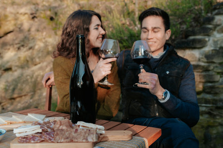 Couple in love having an outdoor aperitif in the garden tasting red wine