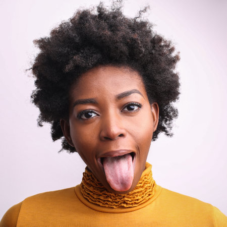 A portrait of a cool African woman with short curly hair sticking out her tongueの写真素材
