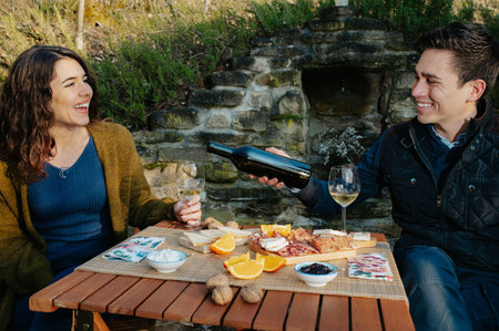 A loving couple having an outdoor lunch in the garden and tasting wineの写真素材