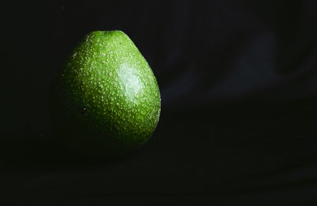 A closeup view of a ripe avocado placed on the surface of a a black clothの写真素材