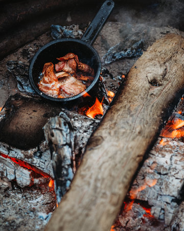 A top view closeup of bacon being cooked on the stove on a campfire while campingの写真素材