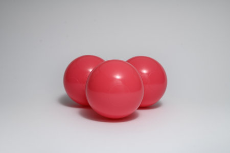 A closeup shot of three red plastic balls on a gray backgroundの写真素材