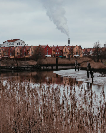 The river called "Geeste" in Bremerhaven, germany with some colorful houses and a smoking chimney of a waste incineration plant in the background.の写真素材