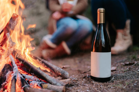 A close-up bottle of wine with copy space by the fire with people in the blurry background.の写真素材