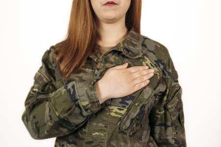 A woman in military camouflage standingwith her hand on her heartの写真素材