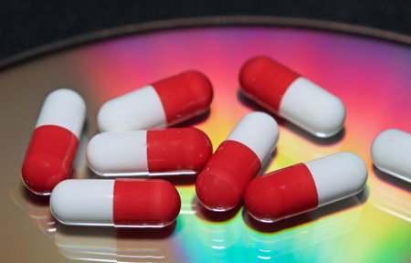 A closeup of the white and red medicine capsules on a rainbow background