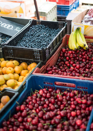 A vertical shot of various berries and fruits on sale in a marketの写真素材