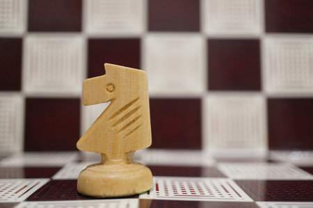 A close-up shot of a white wooden Knight on the chess board