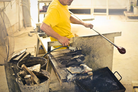 A male with a yellow t-shirt working with his tools to make a glassの写真素材