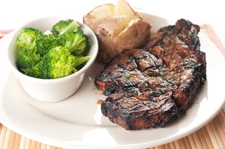 rib steak grilled to perfection with mushrooms, broccoli and baked potatoの写真素材