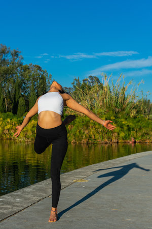 Athlete practices yoga in the morning wearing sportswear with a lake in the background. Concept of freedom.の写真素材
