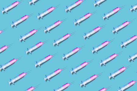 A creative pattern made with a syringe on blue background. New Coronavirus infectionの写真素材