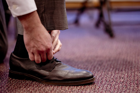 A closeup of a bridegroom tying his shoes on his wedding day