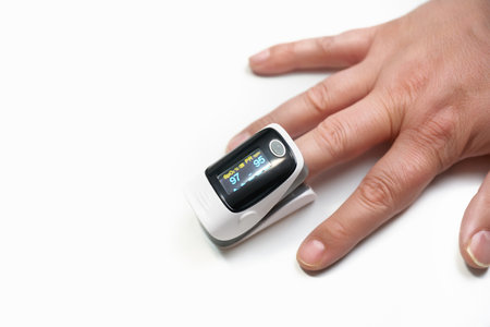 A pulse oximeter on a finger on a white background