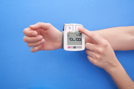 A person measuring his blood pressure with a blood pressure monitor on a blue background