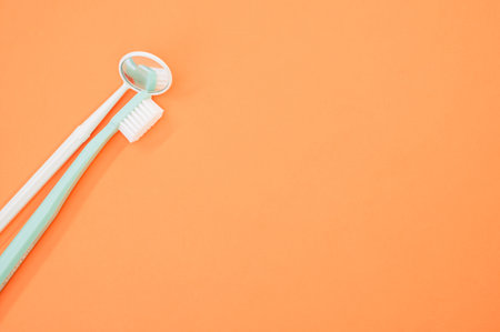 A closeup shot of a dental mirror with a toothbrush isolated on an orange backgroundの写真素材
