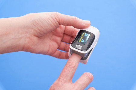 A pulse oximeter on a finger on a blue backgroundの写真素材