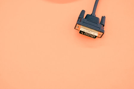 A closeup shot of a DVI cable isolated on a coral background