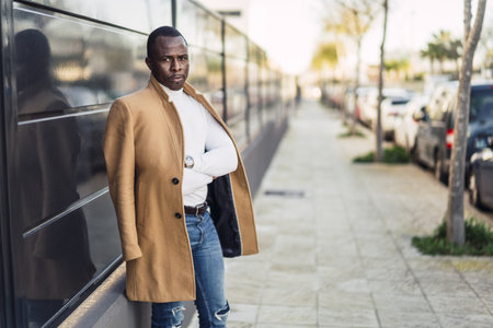 A shallow focus shot of a stylish handsome African male in a coat posing for the camera