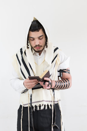A young orthodox Caucasian man praying with a shawl and phylactery against white wallの写真素材