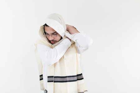 A young orthodox Caucasian man putting on his shawl against white wall
