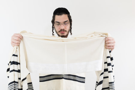 A young orthodox Caucasian man holding a shawl against white wallの写真素材