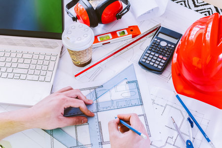 Architect hand holding pencil working with laptop and blueprints for architectural plan, engineer...