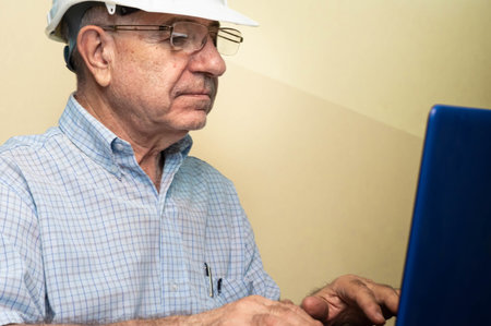 A civil engineer wearing a helmet and working on a laptopの写真素材